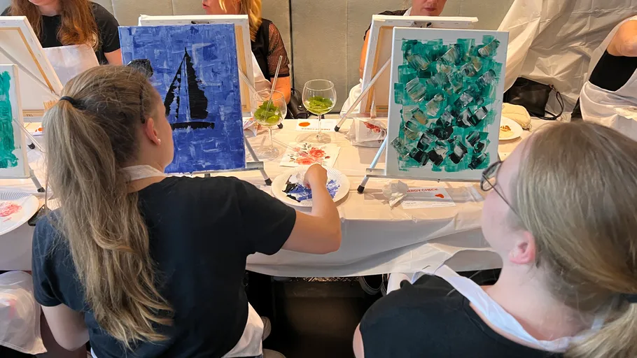 People painting on canvases at a workshop.