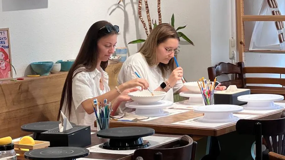 Zwei Frauen bemalen Keramik in gemütlichem Studio.