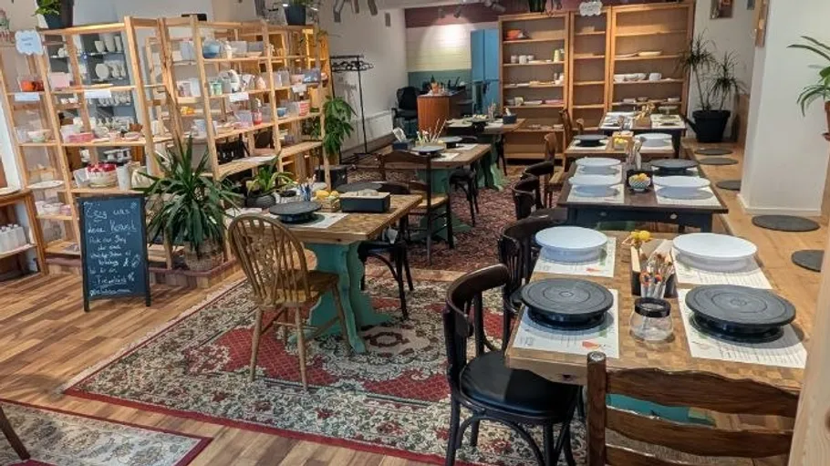 Pottery studio with tables and shelves of ceramics.