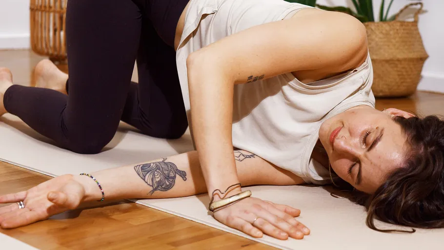 Woman in yoga pose on wooden floor.