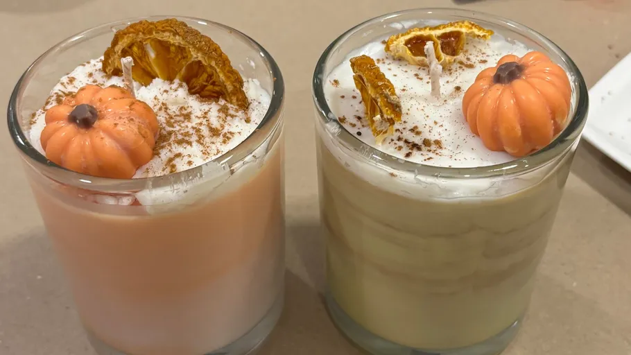 Two pumpkin candles with whipped toppings.