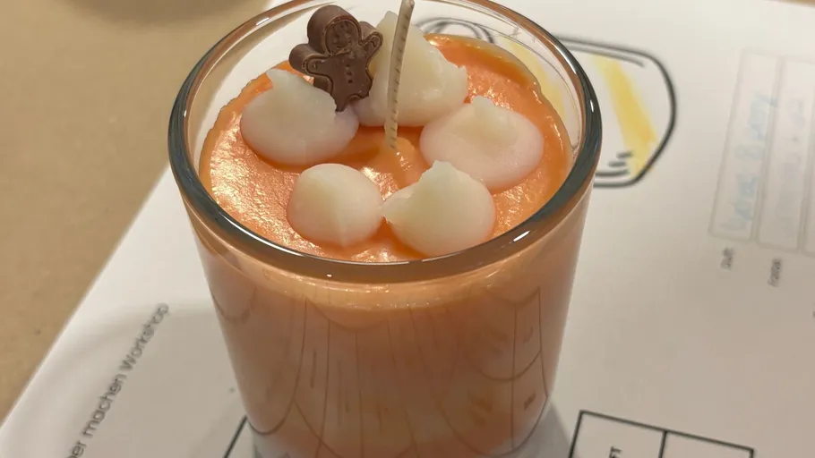 Orange candle with white wax blobs decoration.