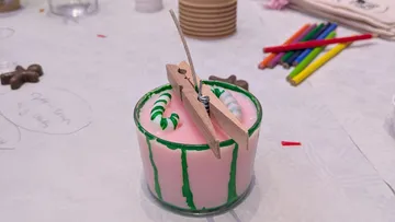 Wooden clothespin holding a candle wick upright.