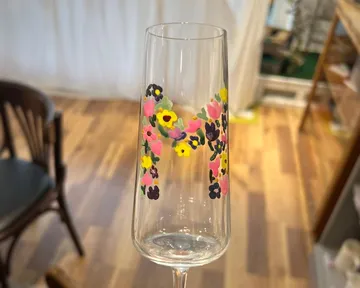 Hand hält ein Glas mit Blumendesign.
