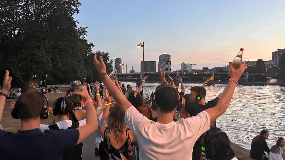 People dancing with headphones by a river.