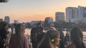 People wearing headphones enjoying a riverside party.