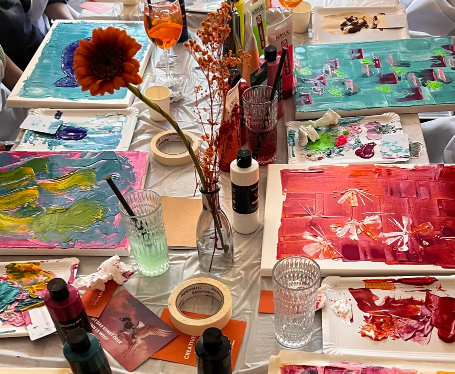 Colorful paintings and art supplies on table.