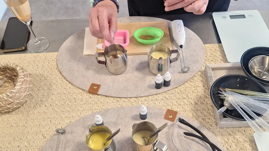 Person making candles on a table.