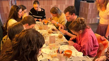 Group painting ceramics at a cafe table.