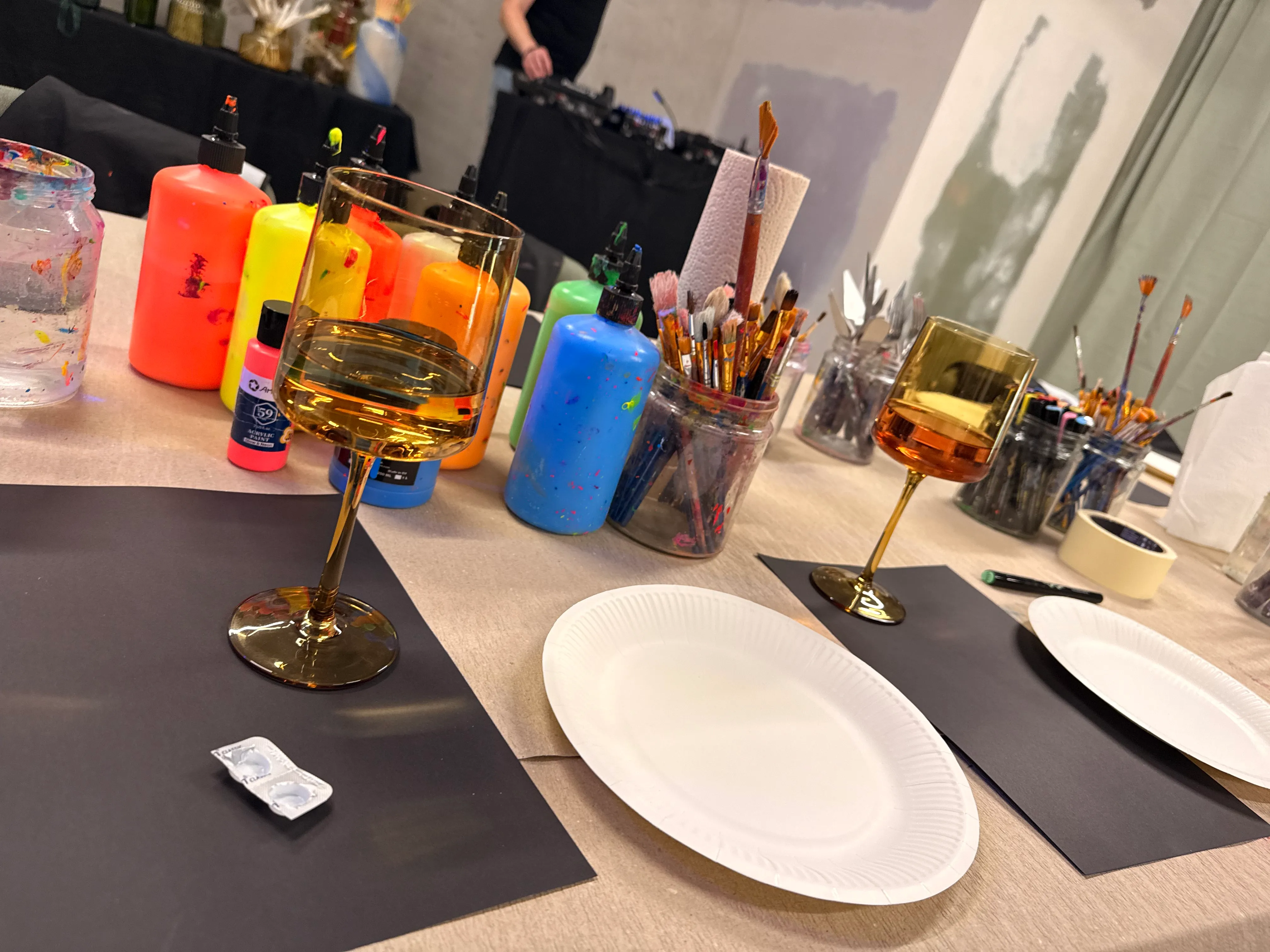 Kunstzubehör auf Tisch mit Weingläsern.
