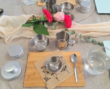 Tischdekoration mit Blumen, Schalen und Kännchen.