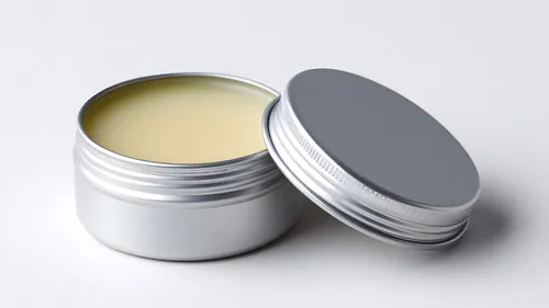 Open tin of balm with lid beside.