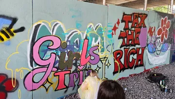 Graffitikünstler malen Wand unter Brücke.