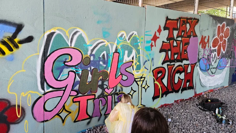 Graffitikünstler malen Wand unter Brücke.