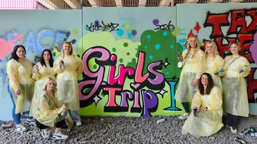 Gruppe Frauen posiert mit Graffiti-Wandbild.