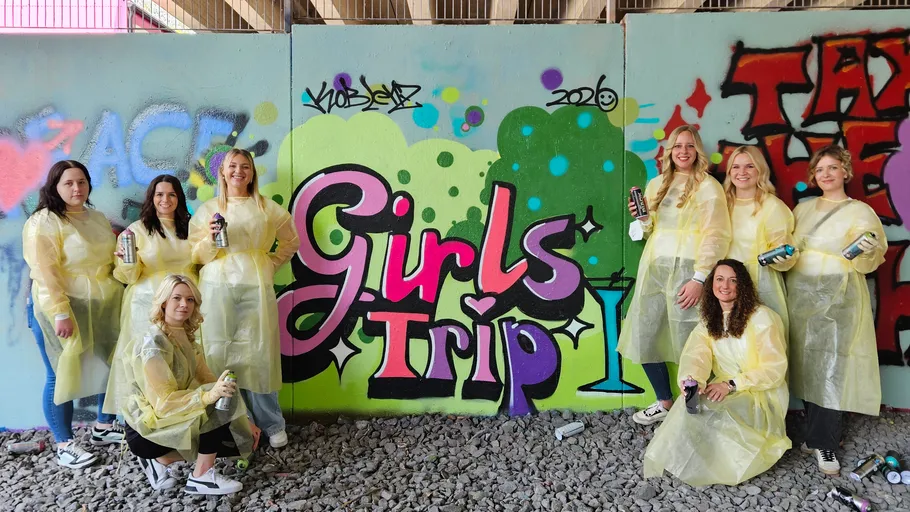 Gruppe Frauen posiert mit Graffiti-Wandbild.