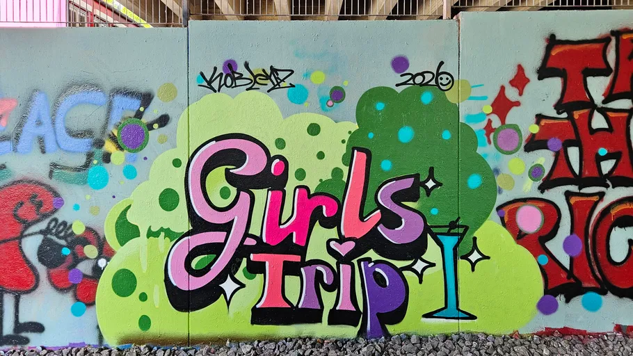 Buntes Graffiti mit 'Girls Trip' an Wand.