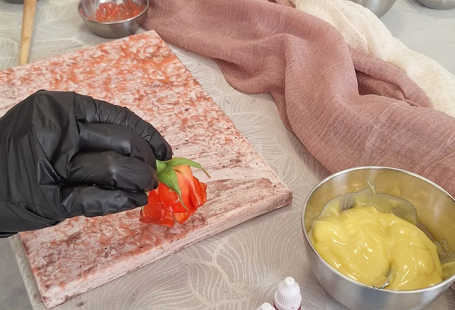 Behandschuhte Hand hält Blume nahe Dessertaufbau.