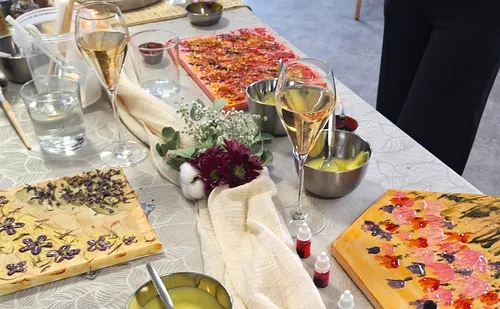 Table set with paintings, drinks, and flowers.