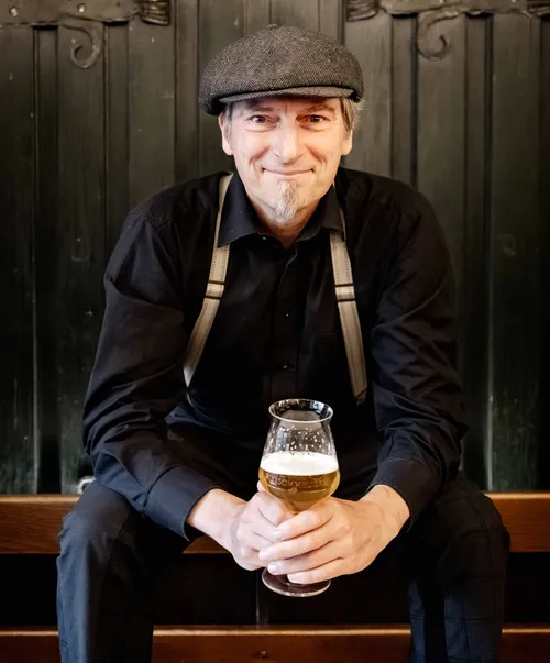 Man sitting with beer glass indoors.