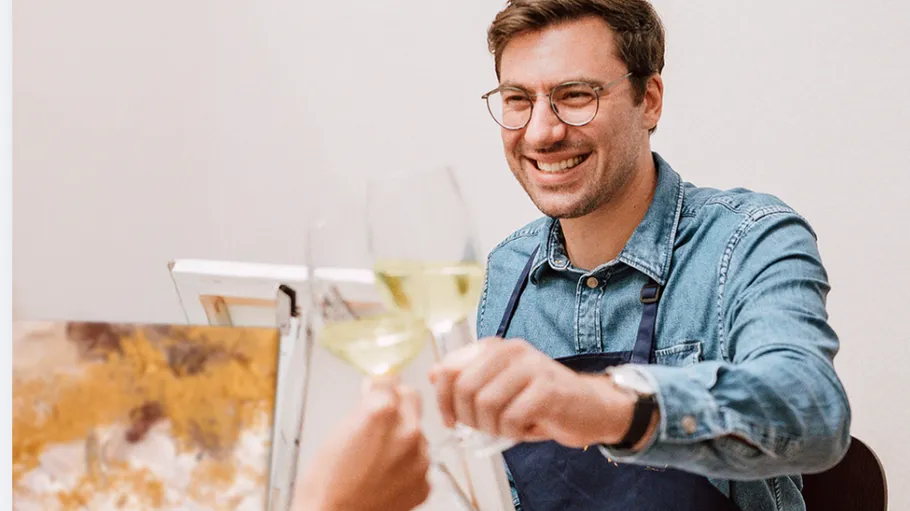 Mann stößt im Malkurs mit Wein an.