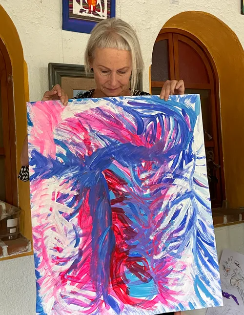 Person holding abstract colorful painting indoors.