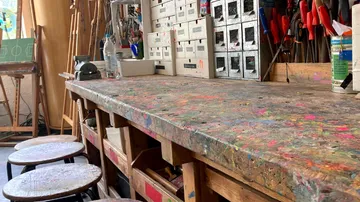 Messy workshop table with tools and shelves.