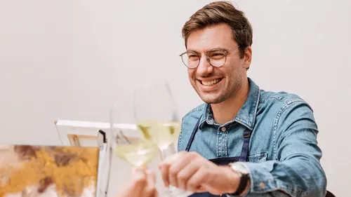 Man smiling while holding a wine glass.