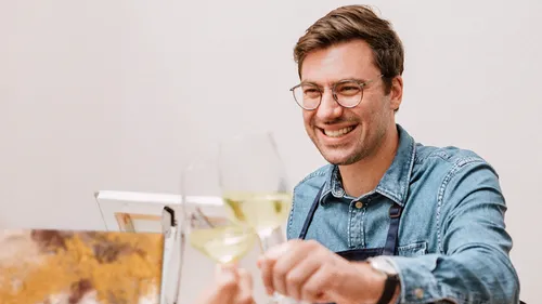 Man smiling while holding glasses indoors.