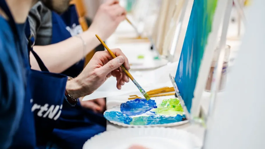 Person painting on canvas with brushes.
