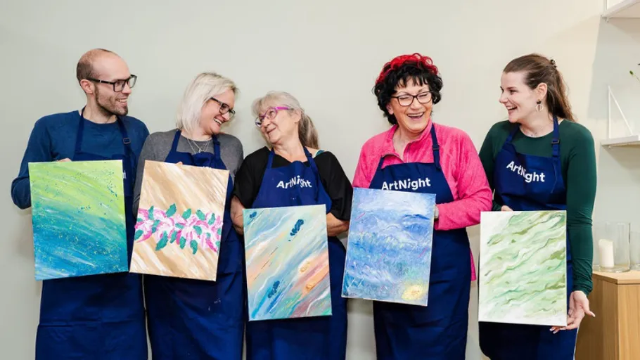 Five people smiling, holding their paintings in aprons.