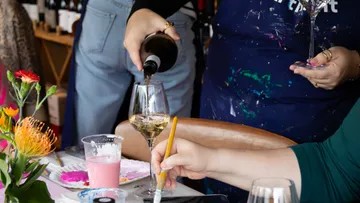 Wein wird beim Malen am Tisch eingeschenkt.