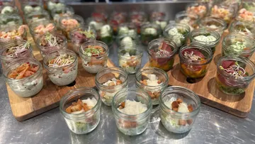 Assorted appetizers in glass jars on wooden boards.