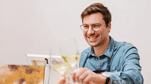 Man holding wine glass, smiling indoors.
