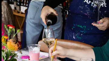 Person schenkt Wein bei Malaktivität ein.