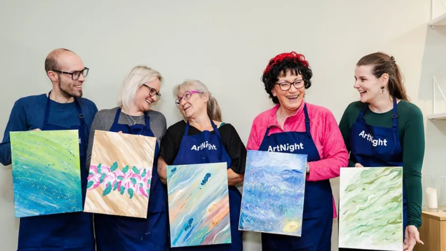 Group of people displaying their paintings indoors.
