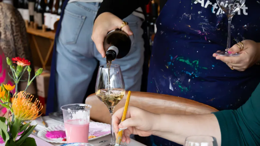 Person gießt Wein während eines Kunstkurses ein.