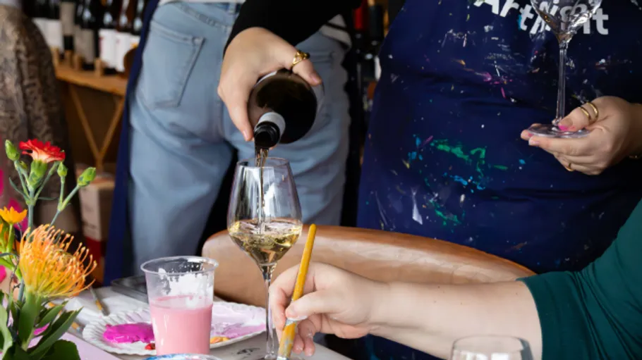 Wein wird bei Kunstveranstaltung eingeschenkt, bunter Tisch.