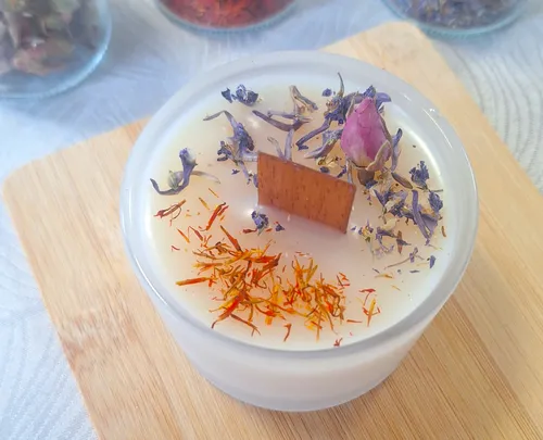 Decorative candle with flowers on wooden board.
