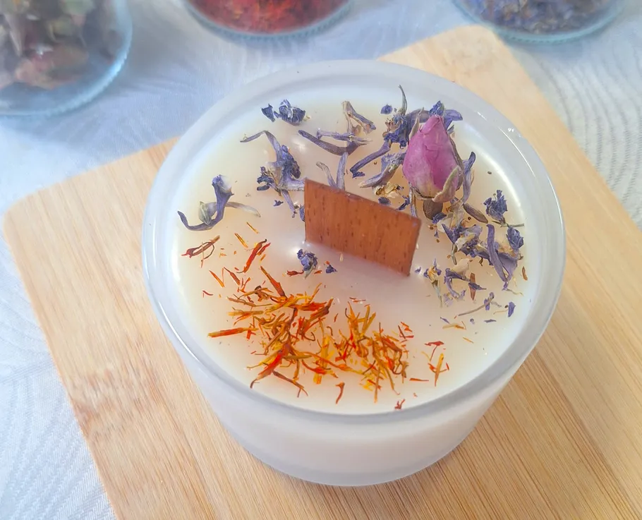 Decorative candle with flowers on wooden board.