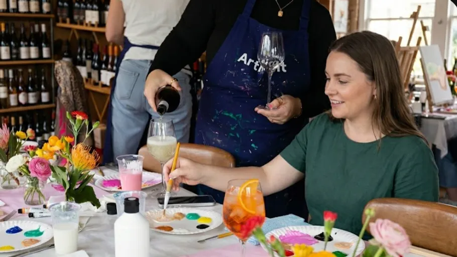 Woman painting at table while wine is served.