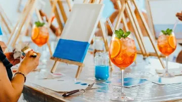 Cocktailglas mit Malerei im Hintergrund.