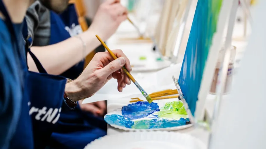 Person painting on canvas in an art class.