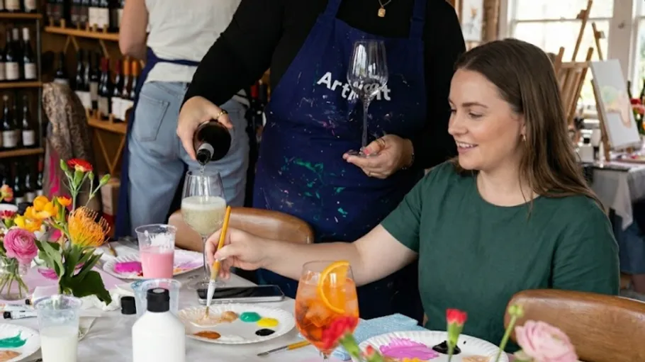 Woman painting at table with drinks poured.