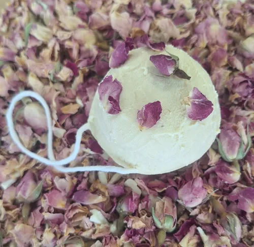 Bath bomb with rose petals on dried roses.