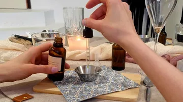 Hands using dropper with oil in a bowl.