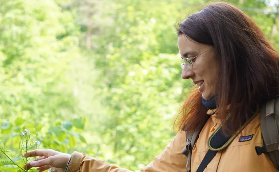Woman pointing at plant in forest.