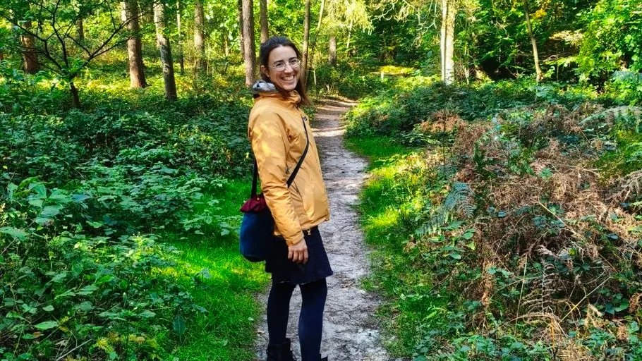 Lächelnde Person auf einem Waldweg.