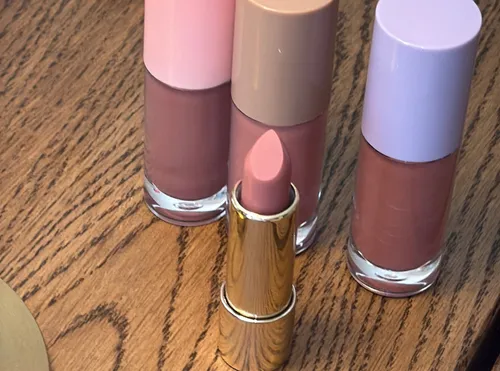 Lipstick and nail polish on wooden table.