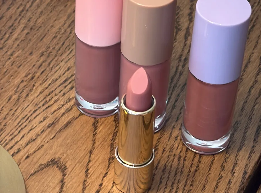 Lippenstift und Nagellack auf Holztisch.